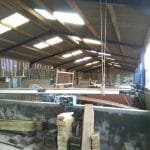 The mast now hanging from the roof to allow the oil drum it was resting on to be used in raising the boat.